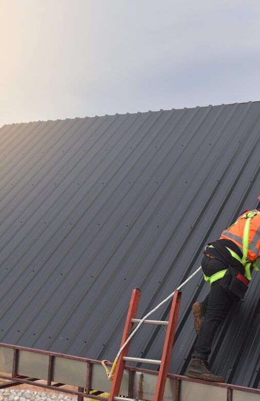 Roofer worker use the ladder in protective uniform wear and glov Roofer worker use the ladder in protective uniform wear and gloves,Roofing tools,installing new roofs under construction,Electric drill used on new roofs with metal sheet.